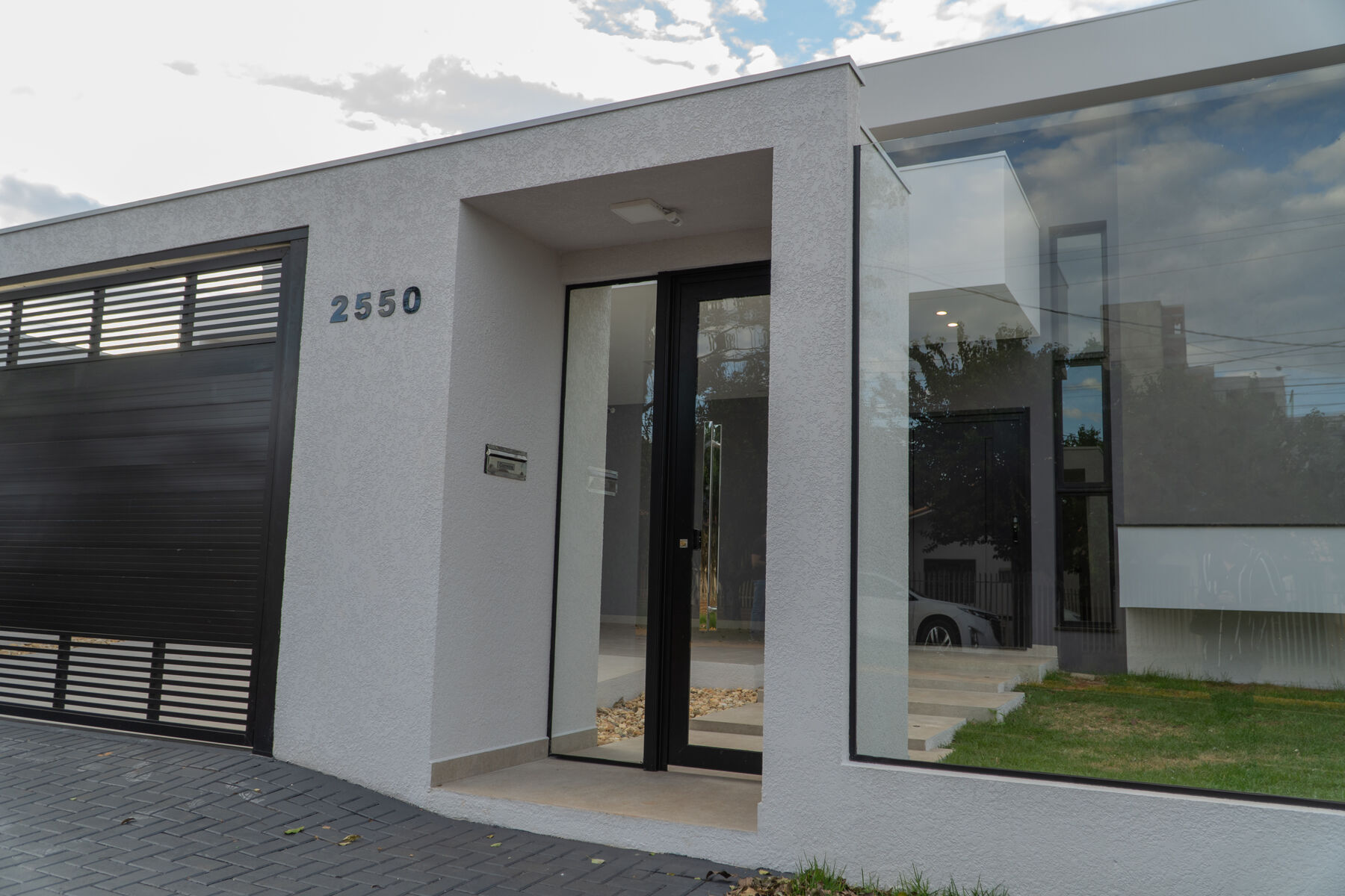 Portão de garagem e porta de entrada em ACM na mesma fachada