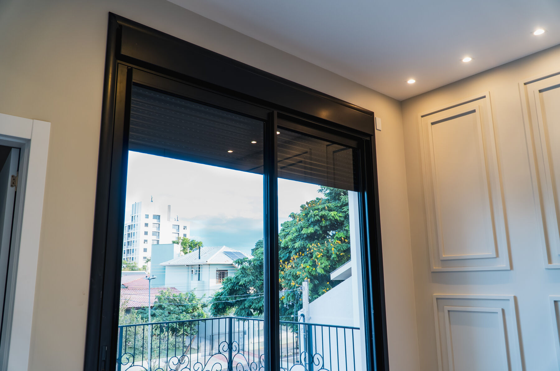 Porta de correr em alumínio com persiana e vista para a cidade